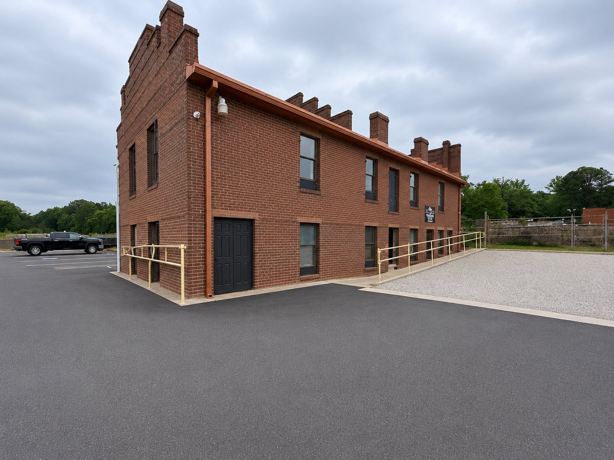 Two-storey brick office building with paved parking and gravel yard